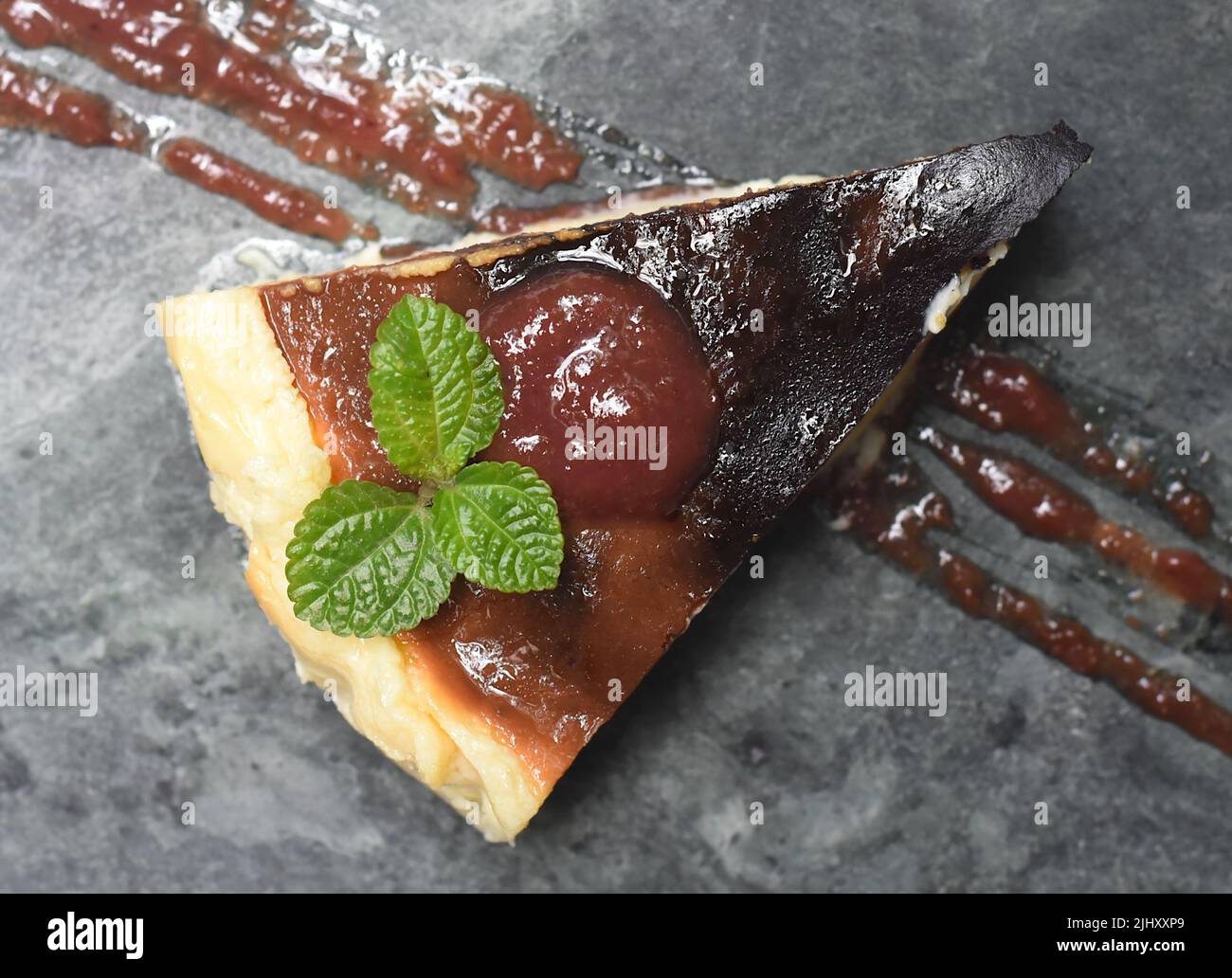 Burnt cheesecake on a stone plate with mint leaf ant toping on gray stone background Stock Photo