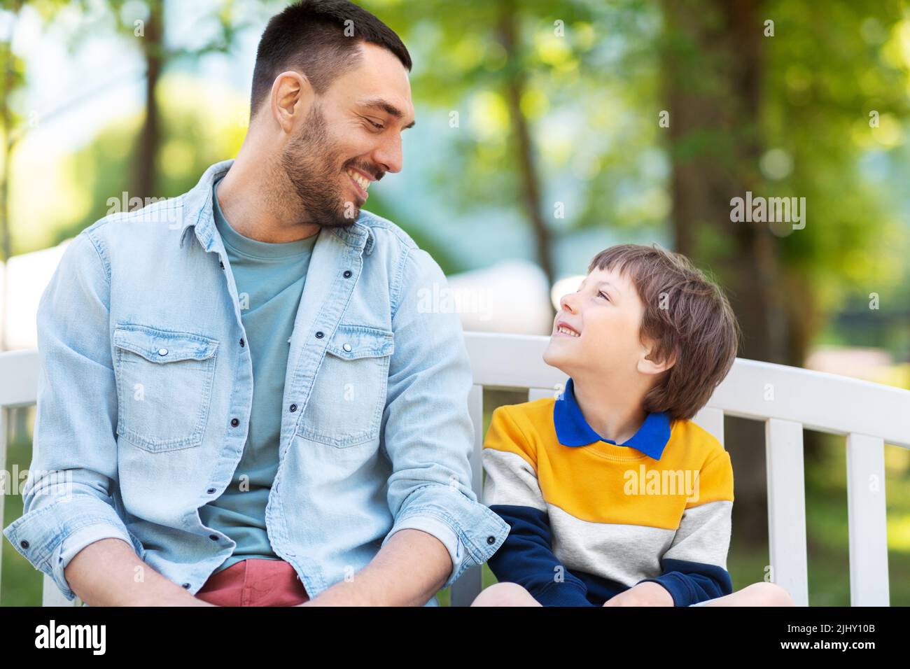 father with son sitting on park bench and talking Stock Photo - Alamy