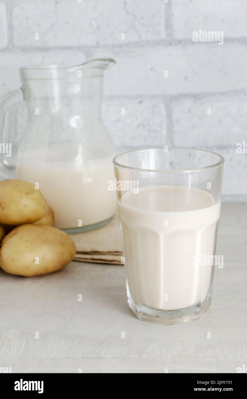 A transparent glass and a jug with potato milk on the table. A new trend in eating healthy