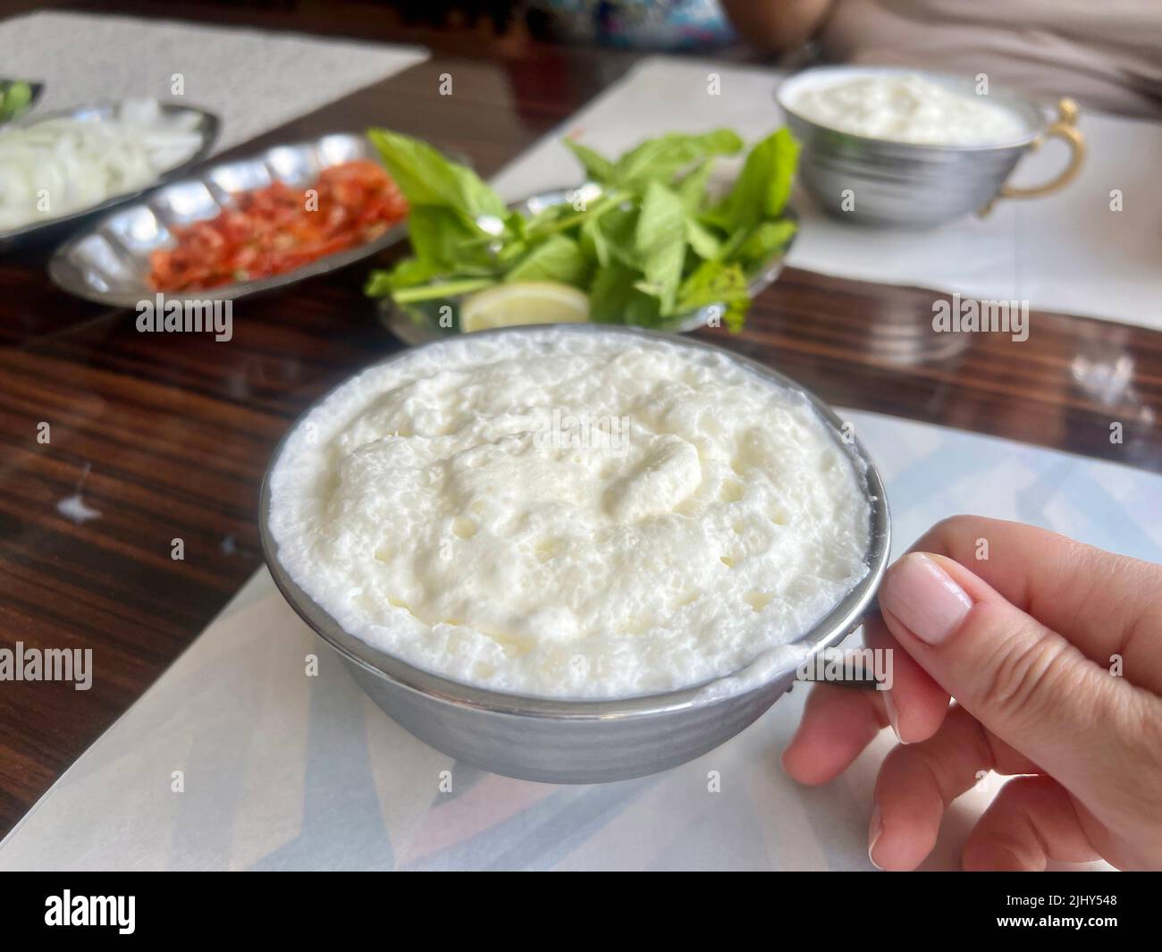 Buttermilk, Traditional yoghurt drink or beverage known as ayran in Turkish with foam in silver metal cup on table in Turkey. Buttermilk, traditional Stock Photo