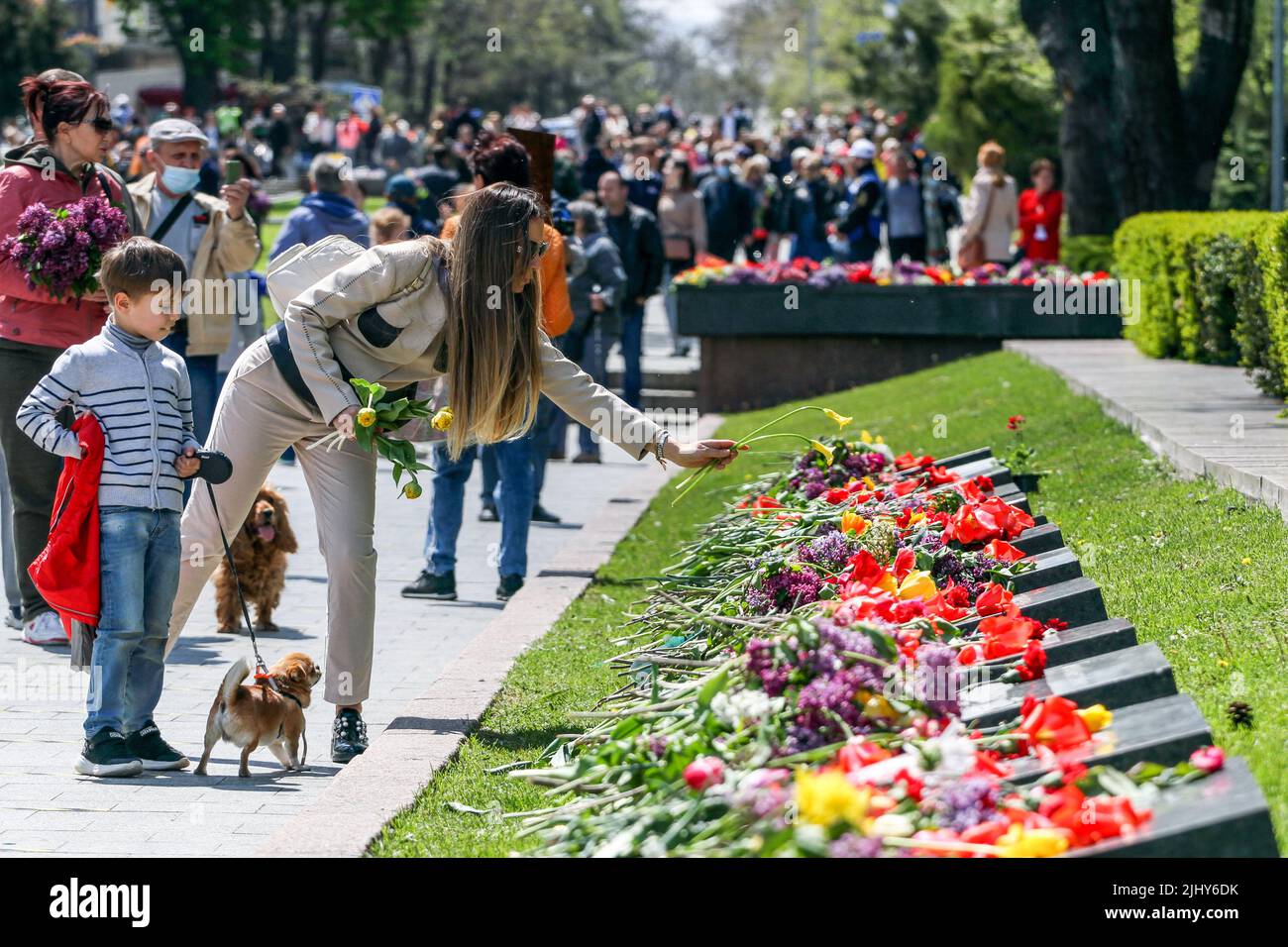 Mother, child and dog are seen laying flowers during the event. On May ...