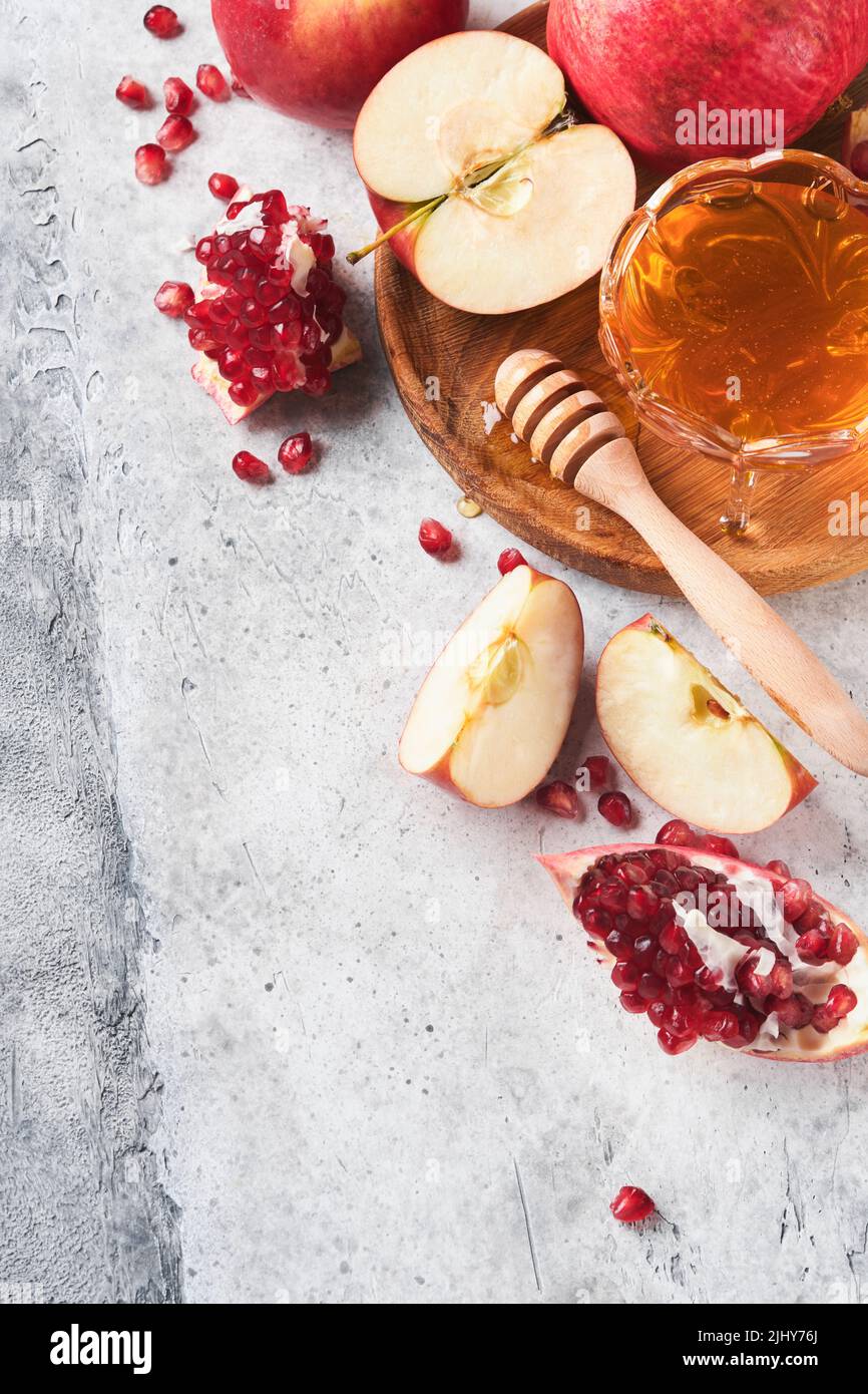 Rosh Hashanah. Pomegranate, apples and honey traditional products for celebration on rustic grey background. Jewish Autumn Rosh Hashana celebration. J Stock Photo