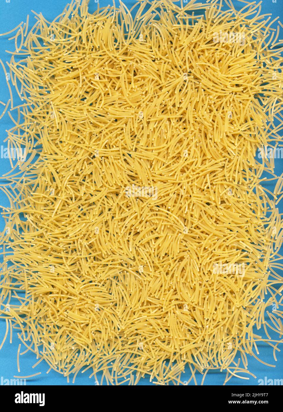Short yellow italian pasta texture on pop blue Stock Photo Alamy