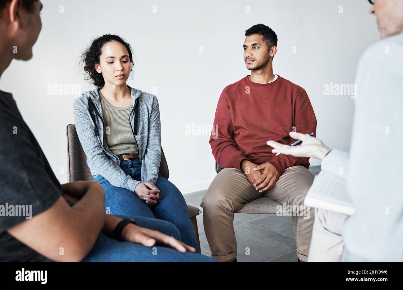 Close up of a young support group during meeting with professional therapist. Group of employees looking serious during a counselling session Stock Photo