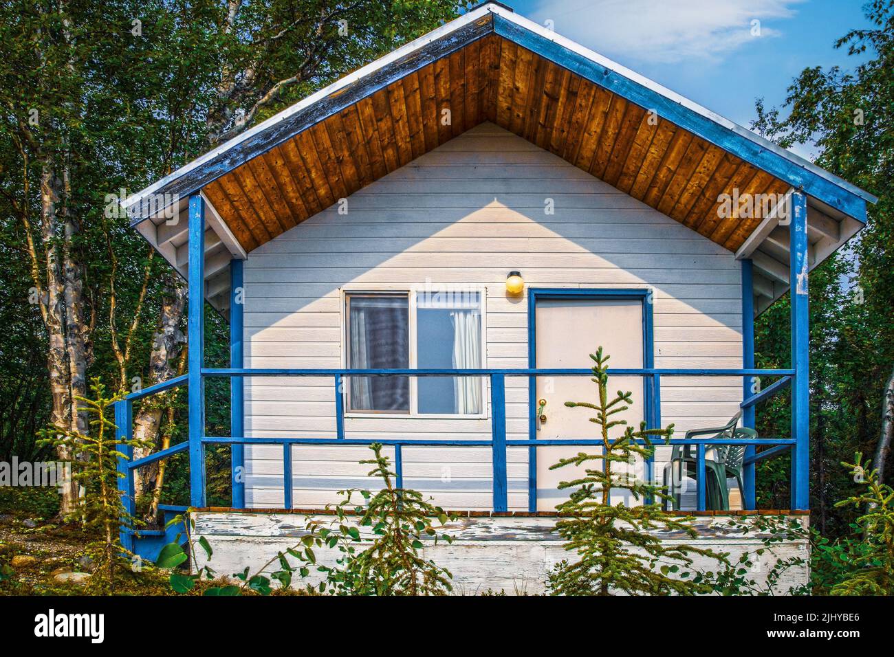 Tiny house in the woods of Alaska - porch with rails and white siding  trimed in bright blue Stock Photo