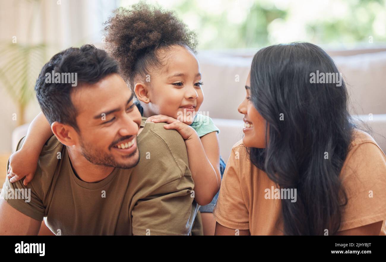 The perfect family. an affectionate young family of three lying on the living room floor at home. Stock Photo
