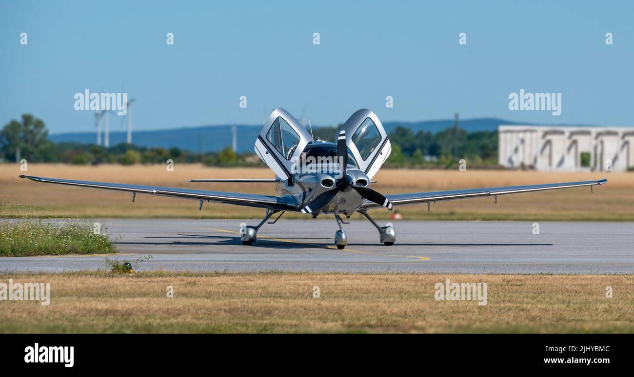 single engine silvery private plane with hinged up gull-wing doors at setdown position on an airport Stock Photo