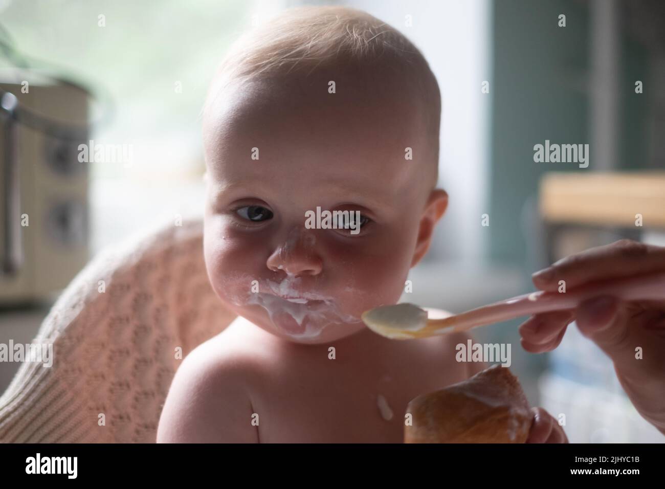 Funny caucasian happy baby boy eating breakfast on the morning. Stock Photo