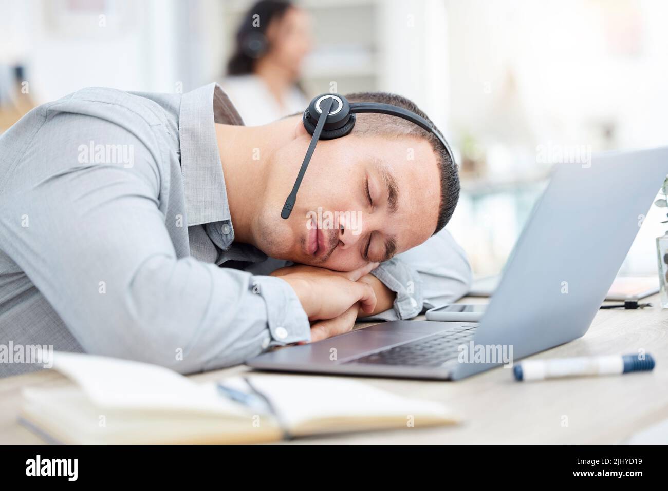 Its been a quiet day. a young call centre agent sleeping at his desk in an office Stock Photo