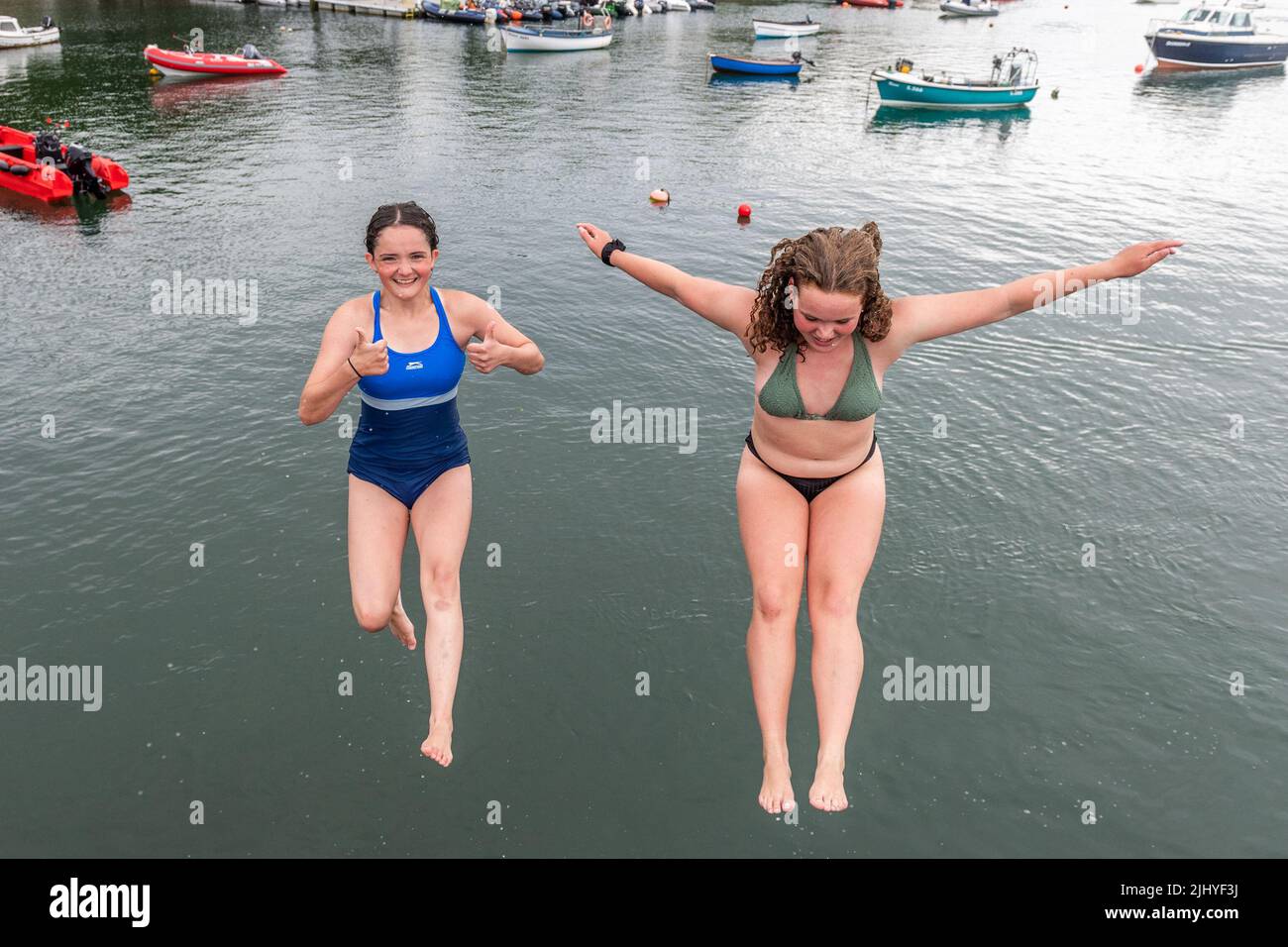 Schull, West Cork, Ireland. 21st July, 2022. On a warm and humid day with temperatures in Schull at 20C, Áine ORegan, Schull and Ella Camier from Ballydehob jump into the water off Schull Pier to cool down. Credit: AG News/Alamy Live News Stock Photo