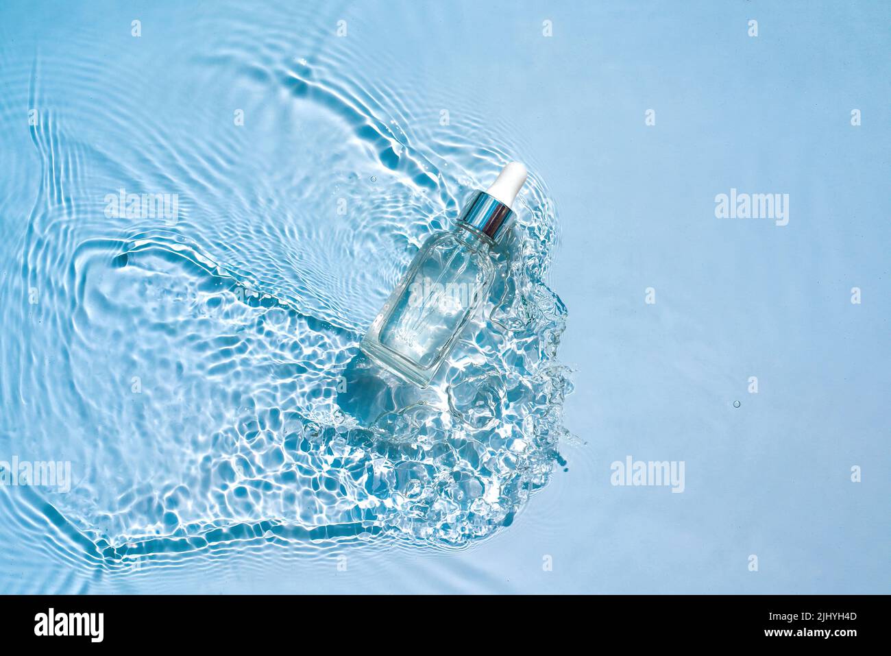 Moisturizing cosmetic product, serum, in transparent bottle in water waves Stock Photo