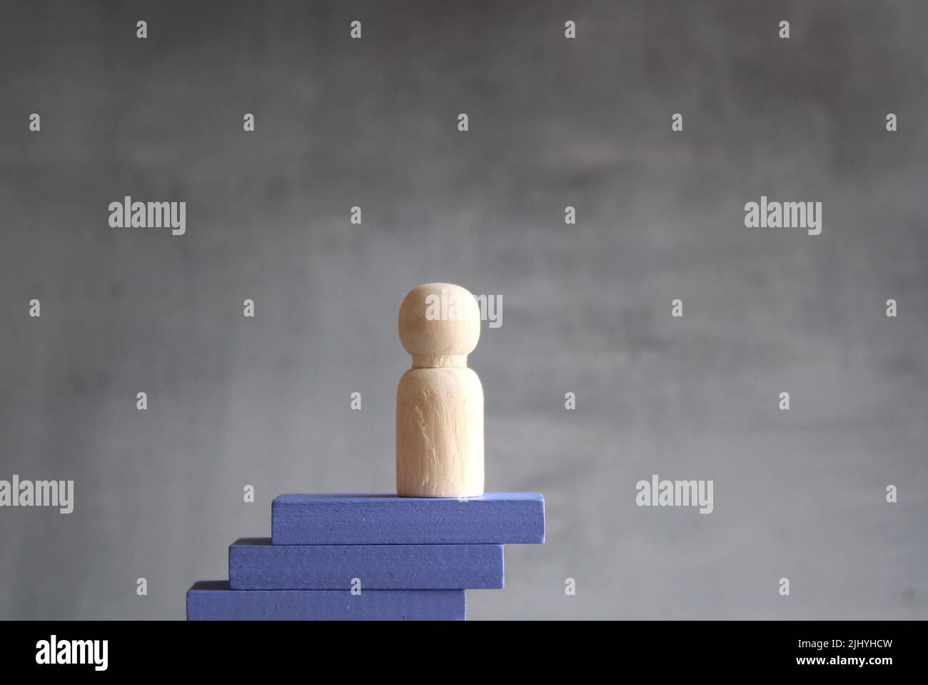 Wooden doll on top of wooden stairs. Concept of business success, social or career ladder. Stock Photo