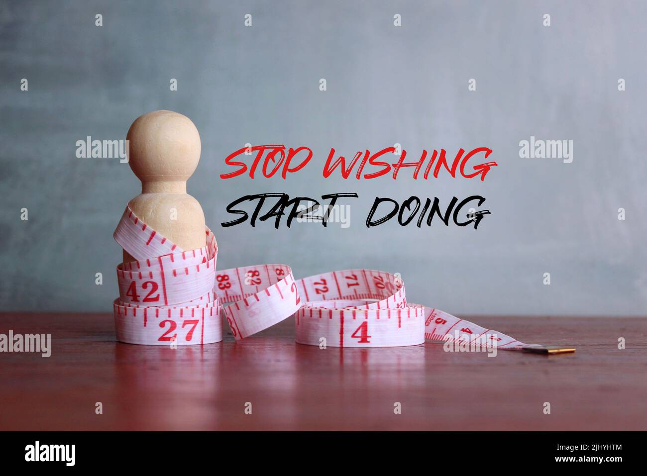 Fitness and motivational quotes. Wooden doll and measuring tape with text 'STOP WISHING START DOING' Stock Photo