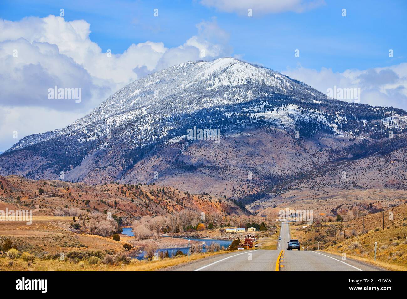 Twolane paved road in mountains leading towards huge snowy mountain in