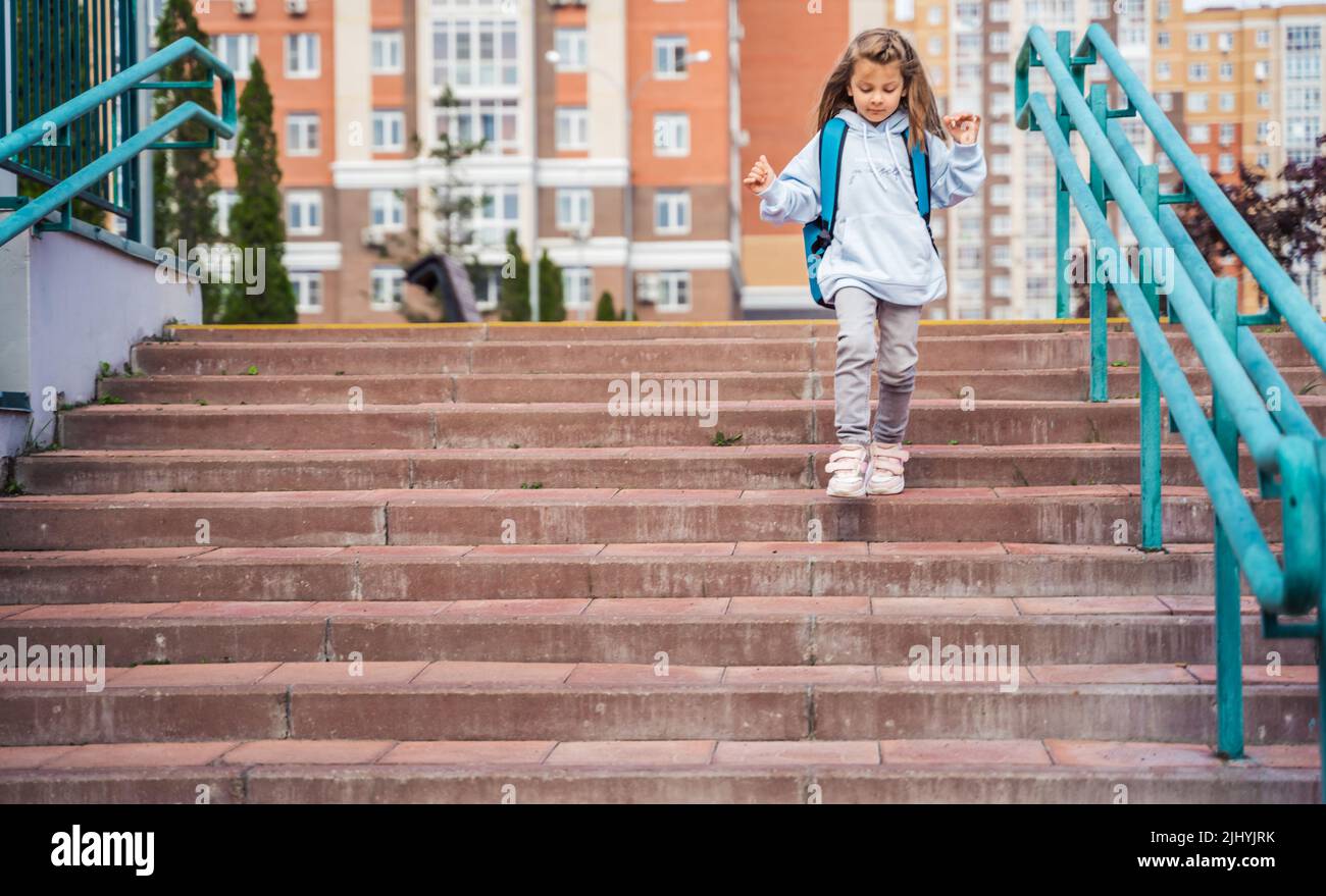 Back to elementary, primary school. Little sad girl with big backpack ...