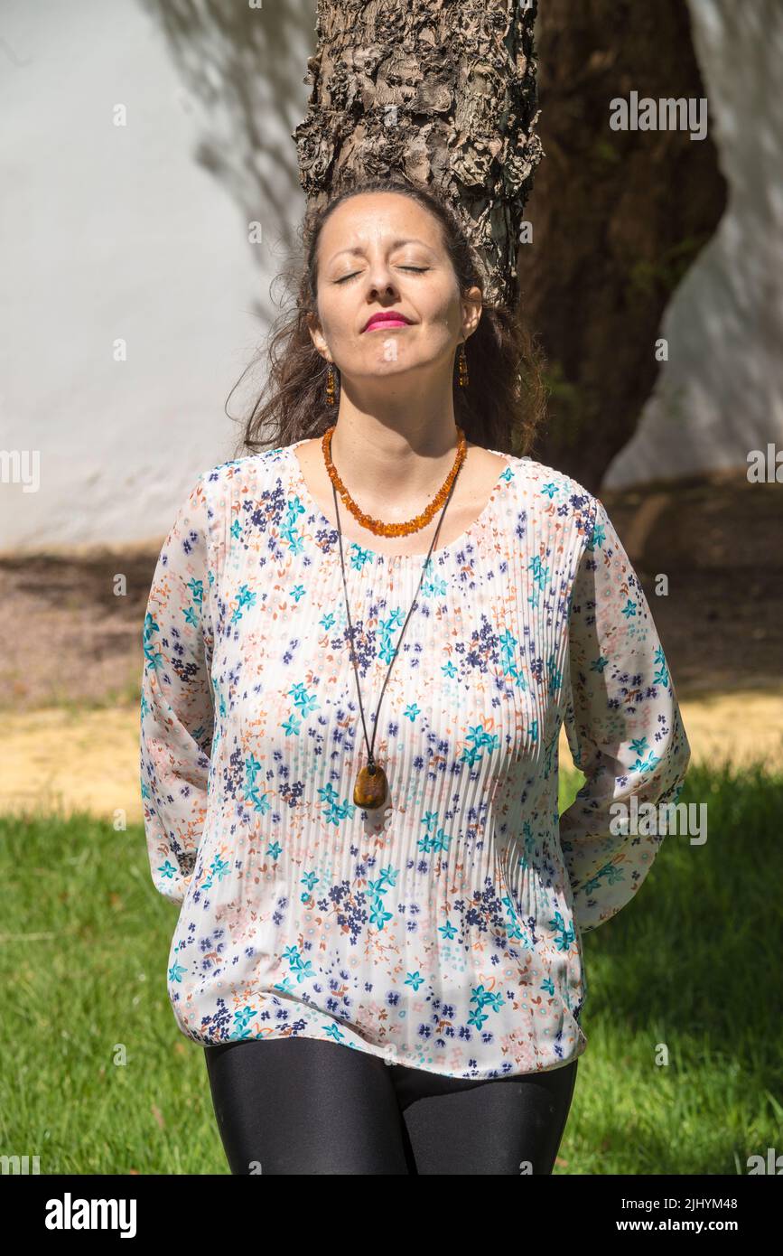 A woman sunbathes standing and hugging a tree. Hugging a tree has many