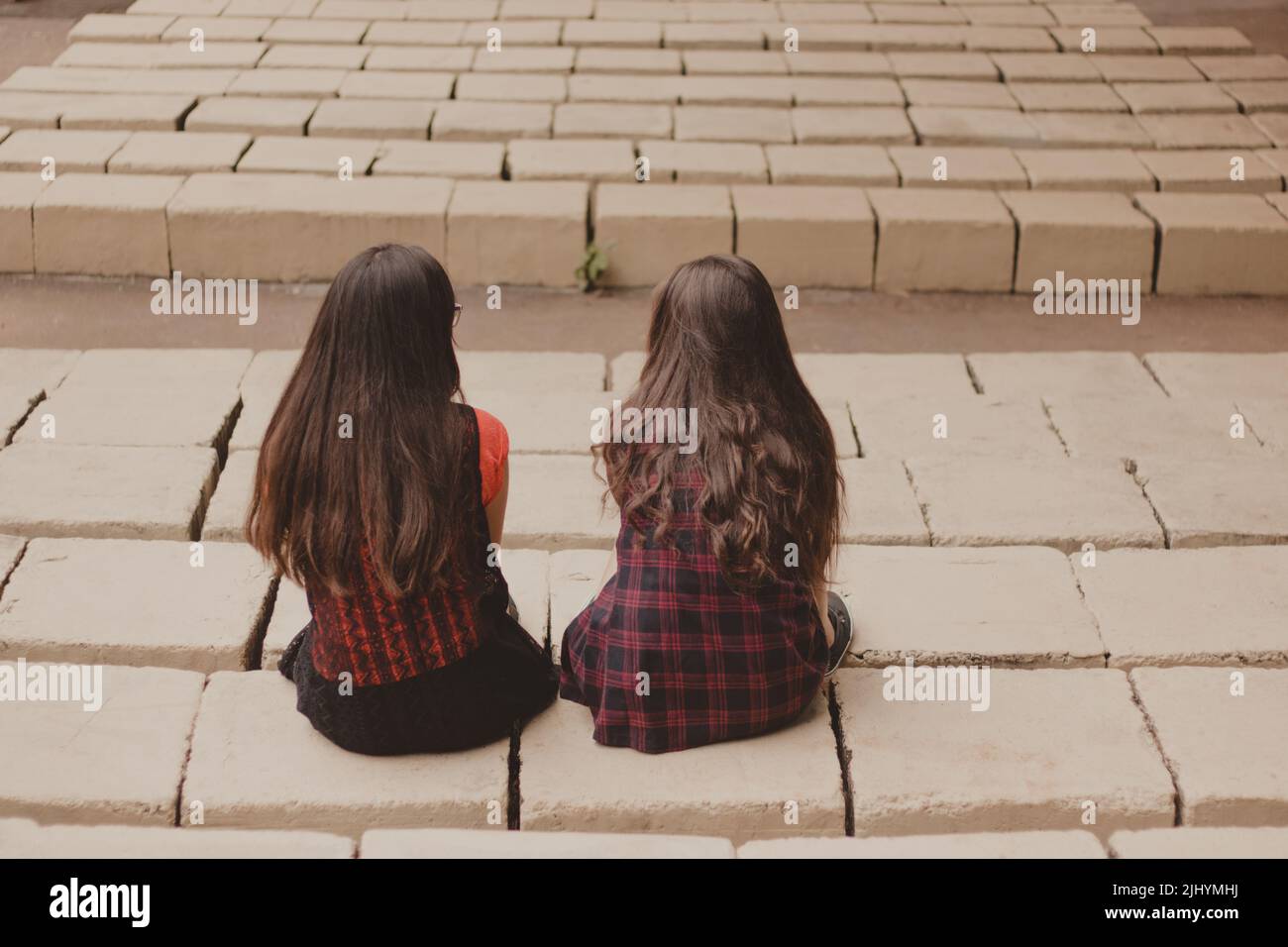 two teenage girl friends backwards sitting next to each other Stock Photo