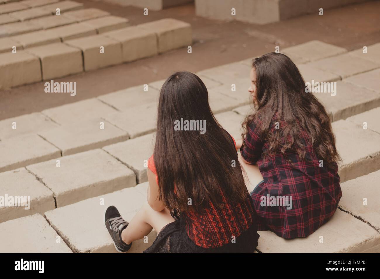 two young woman backwards sitting next to each other Stock Photo