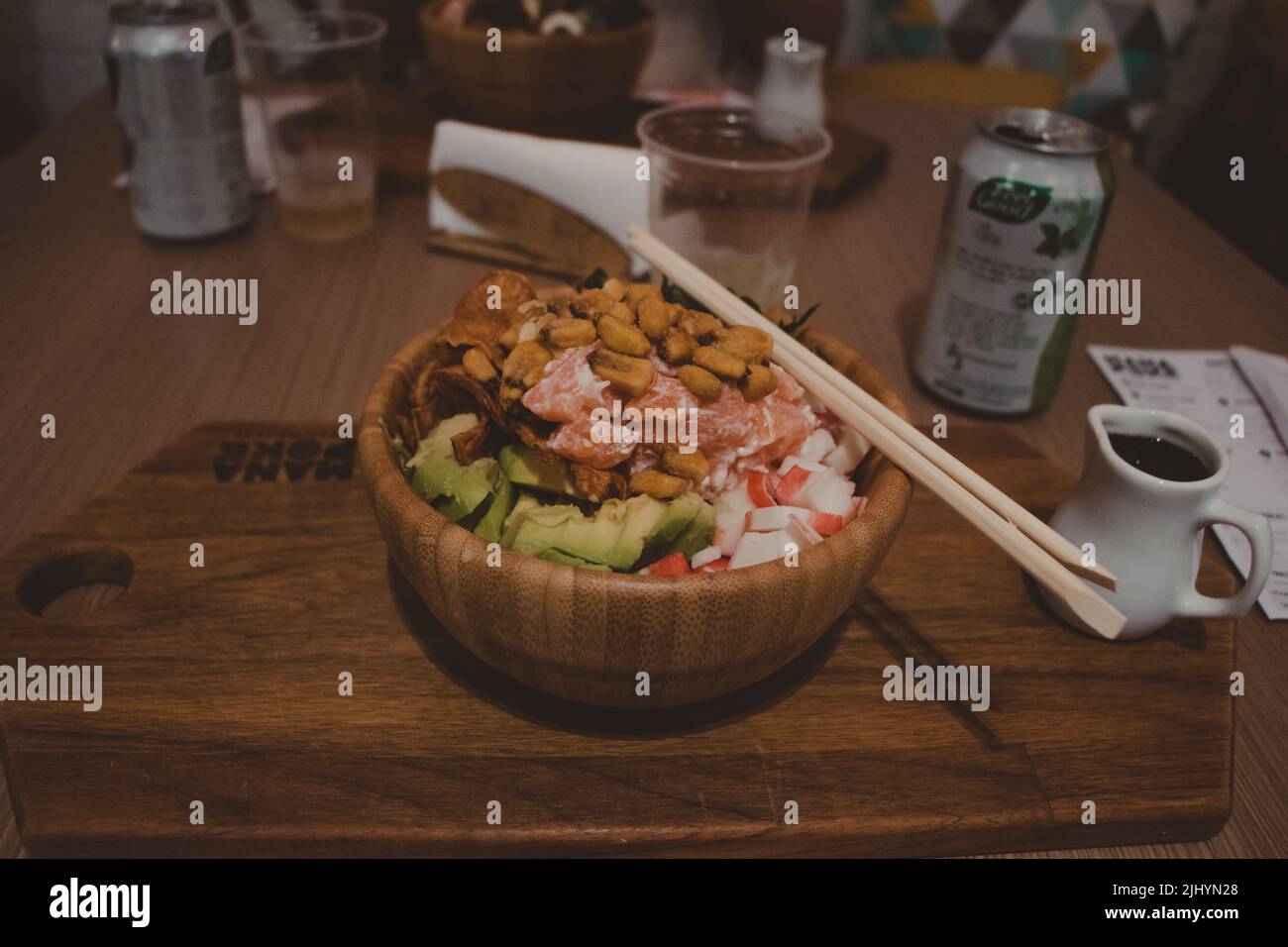 wooden bowl of poke with assorted healthy food and chopsticks on the side Stock Photo