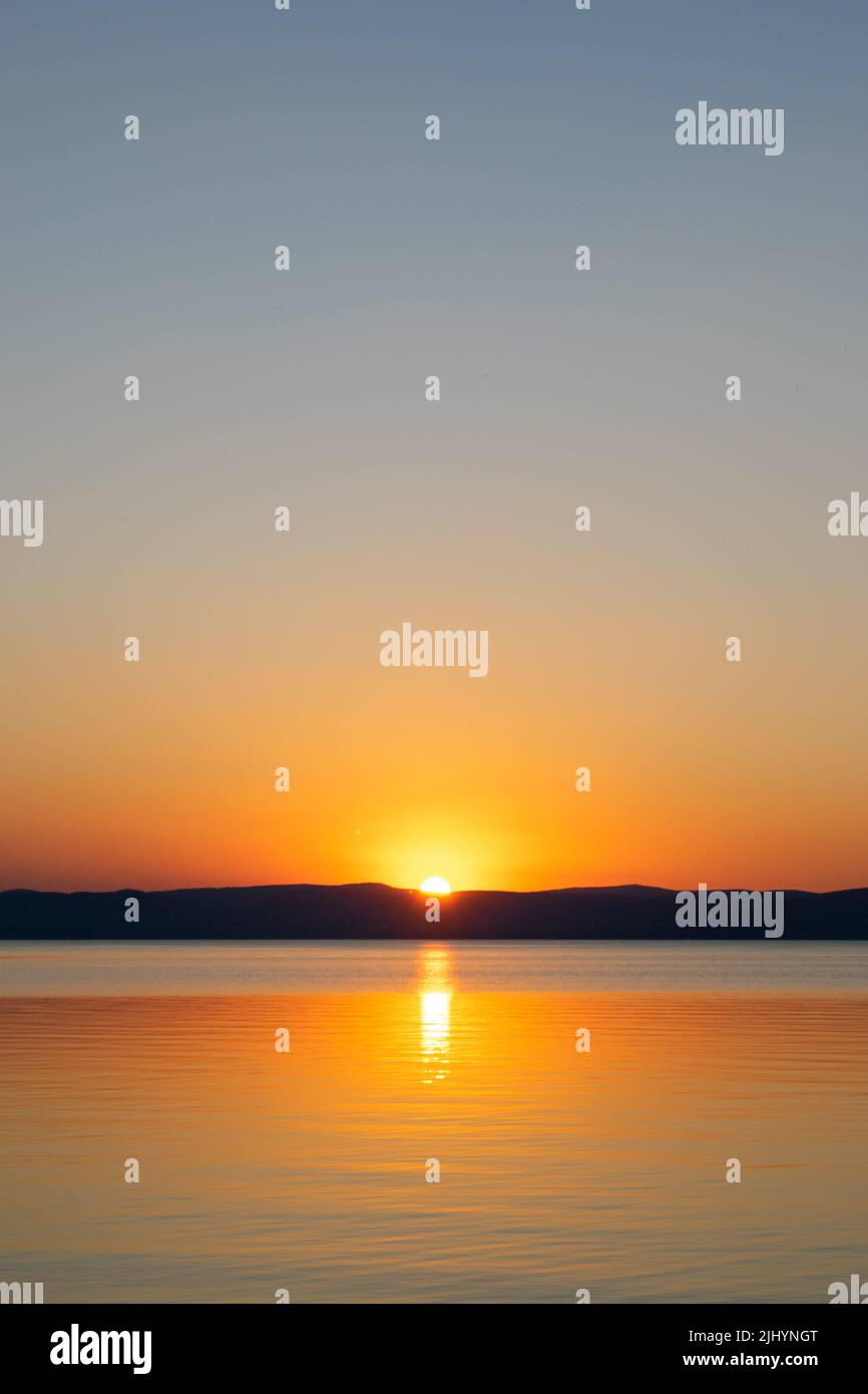 Sunset reflecting on the surface of a lake Stock Photo - Alamy