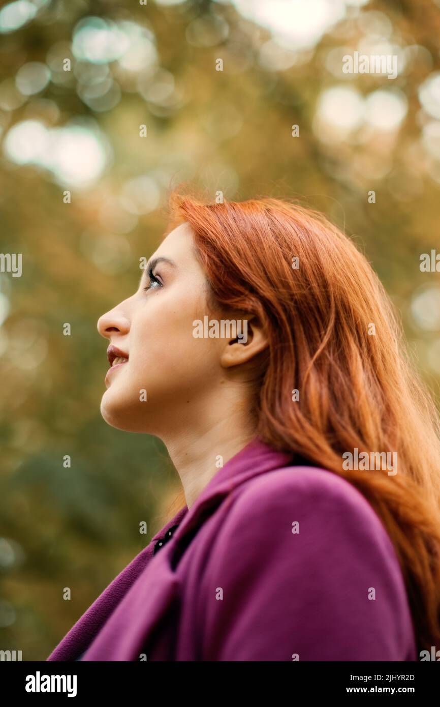 Autumn portrait of candid beautiful red-haired girl with fall leaves in hair. Stock Photo