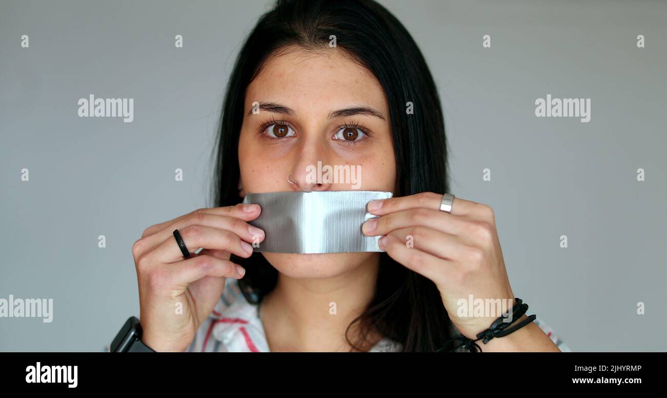 Censored young woman putting mouth tape unable to speak up. Silenced