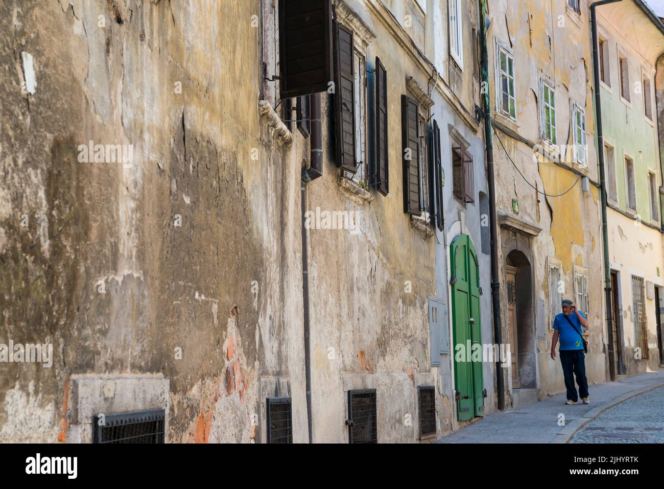 Male person in blue t shirt walking  along old unkempt houses in the old town of Ljubljana, Slovenia Stock Photo