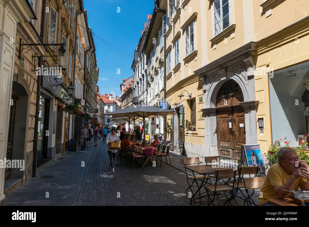 Café - restaurant tables,chairs and sunshades in a narrow street in old part of Ljubljana, Slovenia. Stock Photo