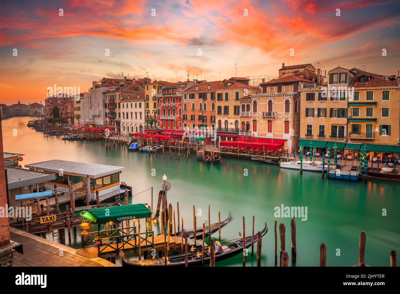 Venice, Italy overlooking boats and gondolas in the Grand Canal at dusk. (Sign reading in Italian 'No Mafia Venezia e Sacra' translates in English to Stock Photo