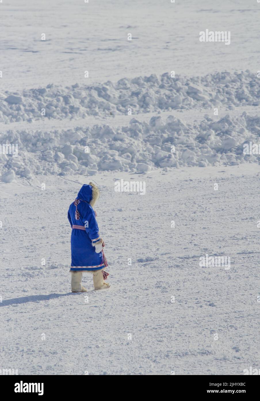 Woman walking on snow wearing traditional parka and mukluks in winter, in Tuktoyaktuk, Northwest Territories, Canada. Stock Photo