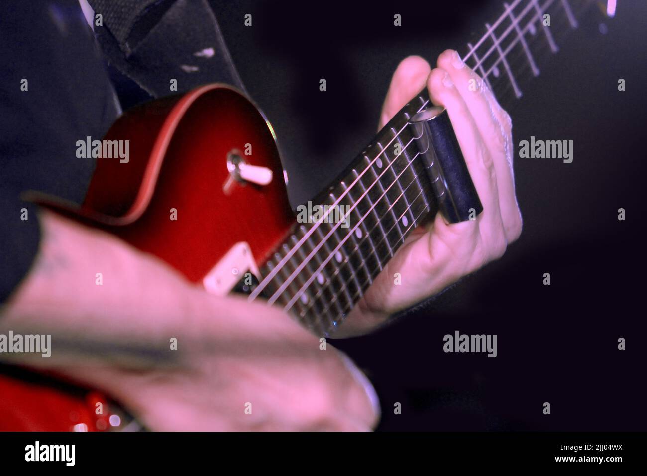 A musician plays electric guitar using a finger slide Stock Photo Alamy
