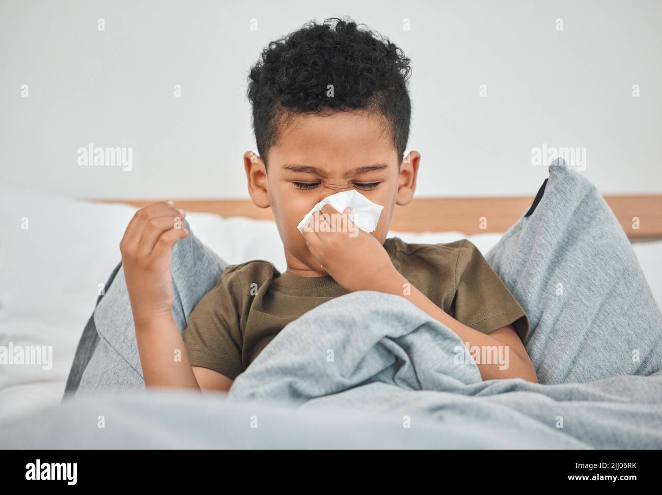 Have to get better soon a little boy blowing his nose while in bed a