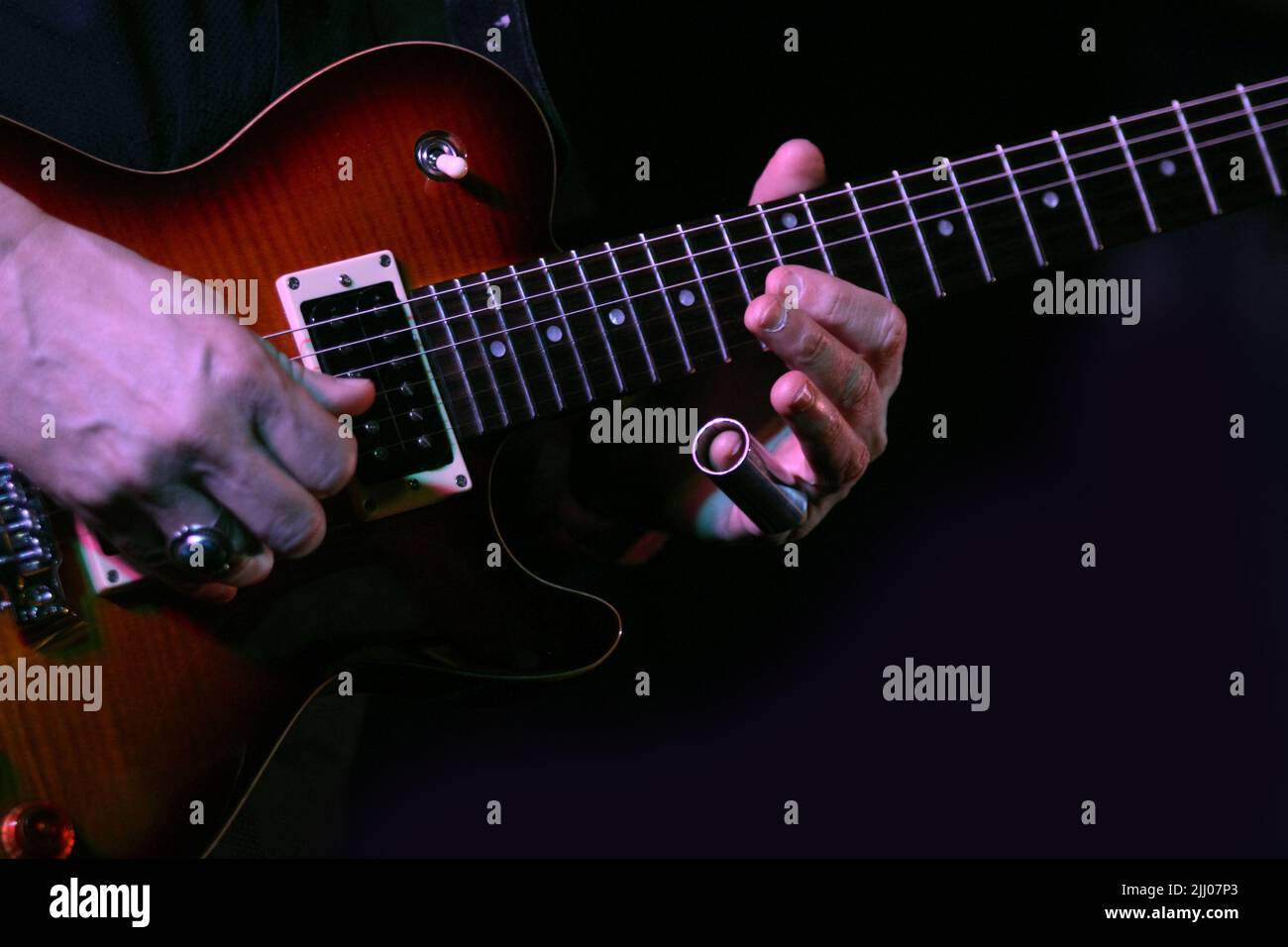 A musician plays electric guitar using a finger slide Stock Photo Alamy