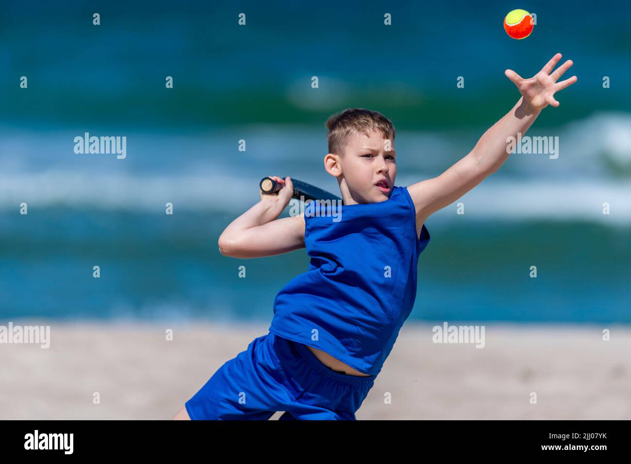 Young boy playing tennis on beach. Kids sport concept. Horizontal sport theme poster, greeting cards, headers, website and app Stock Photo