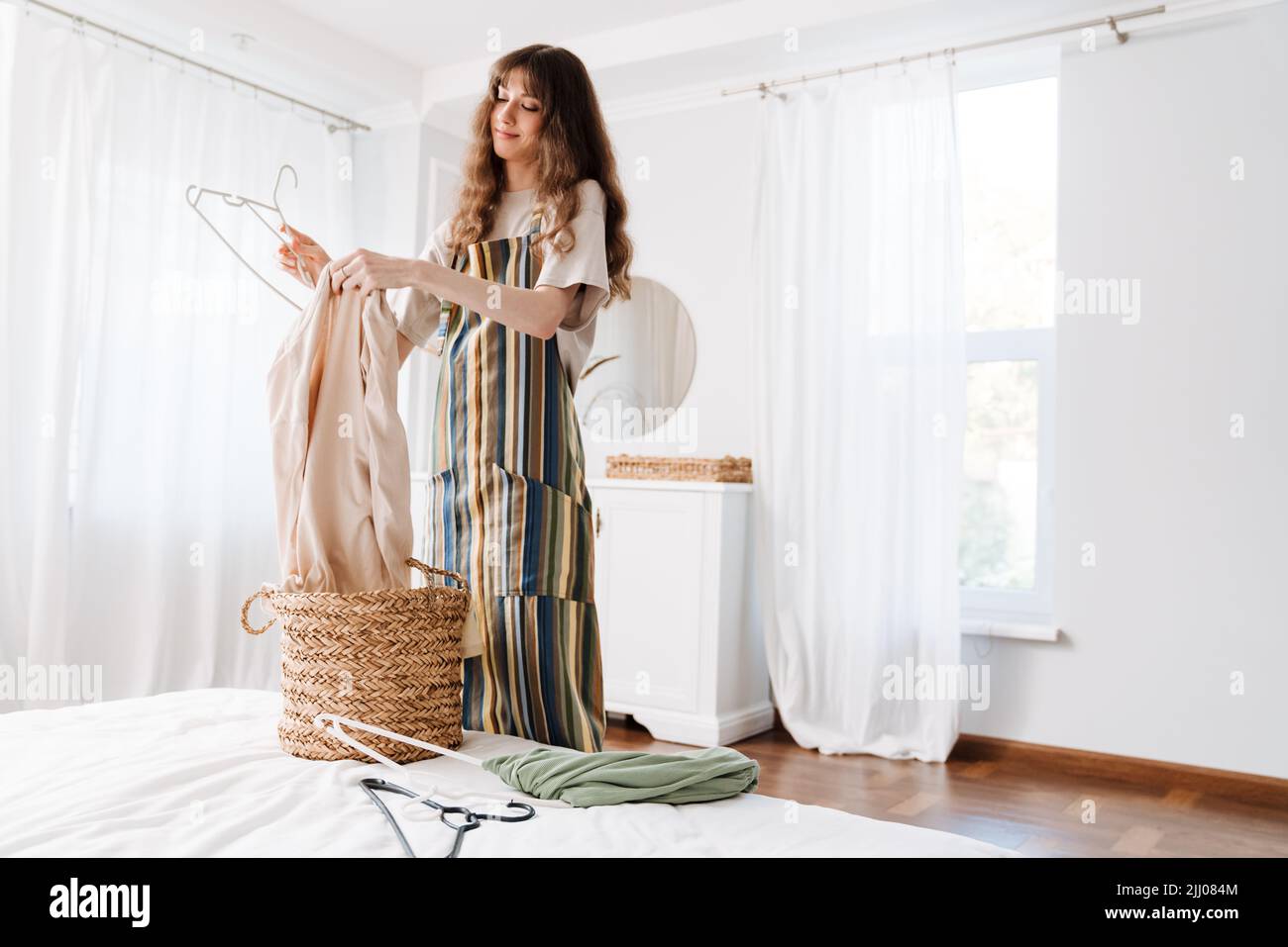 White young woman in apron smiling while doing housework at home Stock Photo