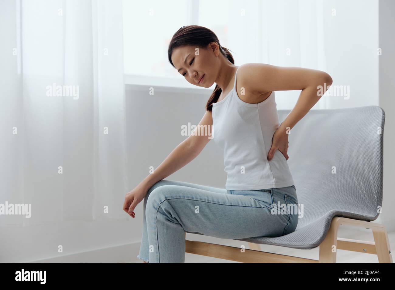 Suffering from scoliosis osteochondrosis after long study pretty young  Asian woman feel hurt joint back pain laptop in incorrect posture sit on  chair Stock Photo - Alamy