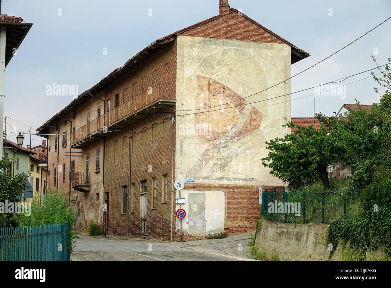 Giant portrait of Benito Mussolini made in 1936 still visible on the side facade of a building.  Montà d'Alba, Italy - July 2022 Stock Photo