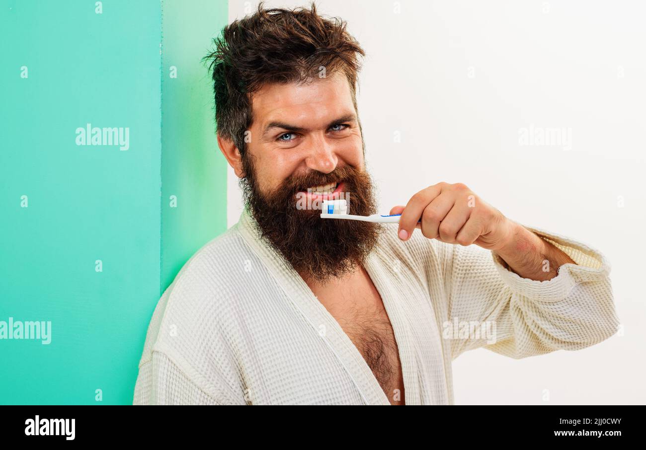 Man brushing teeth with toothbrush and tootpaste. Oral care. Dental hygiene. Bearded guy in bathrobe. Stock Photo