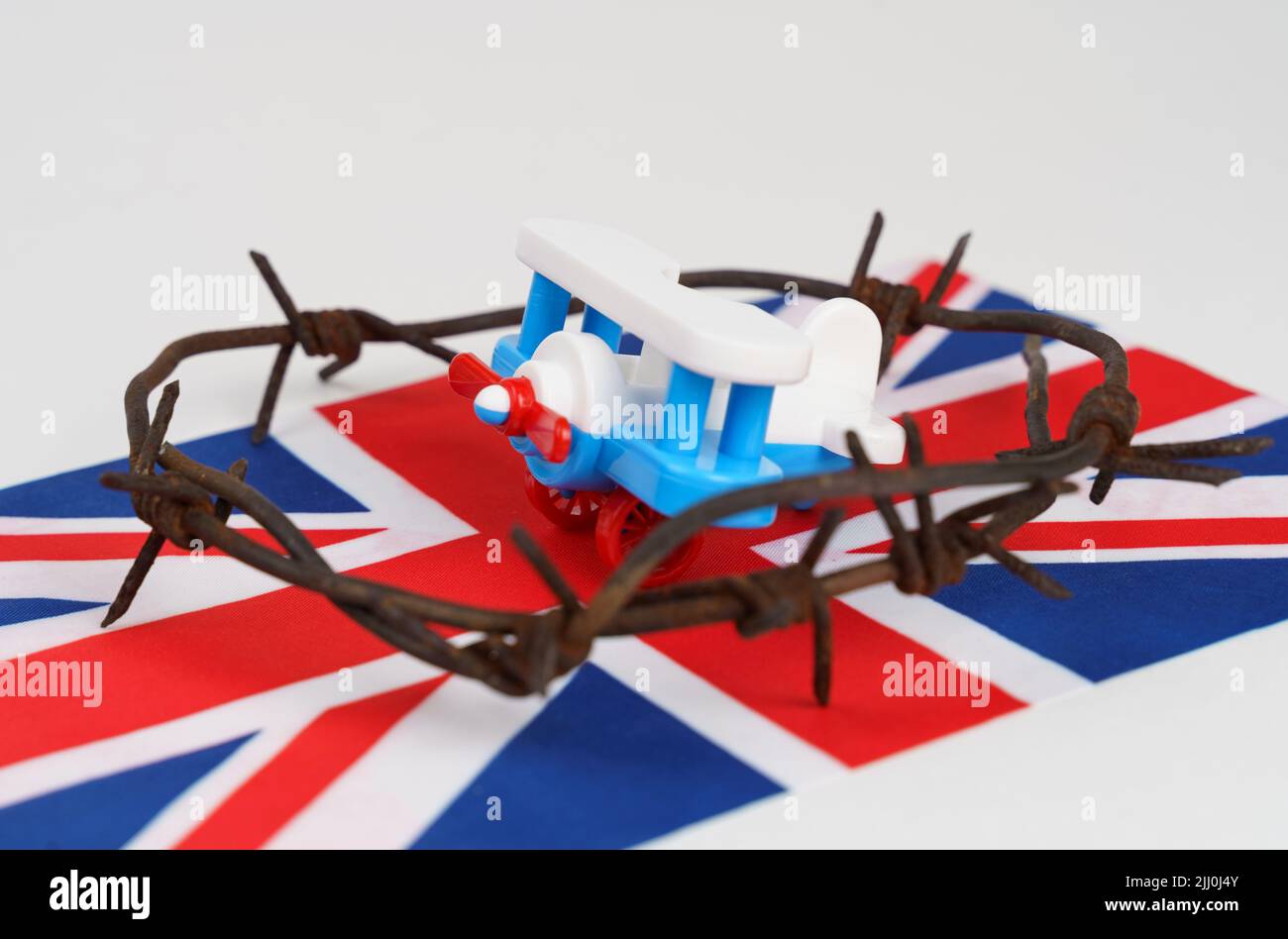 Toy plane, UK flag and barbed wire on a white background. Flying ban