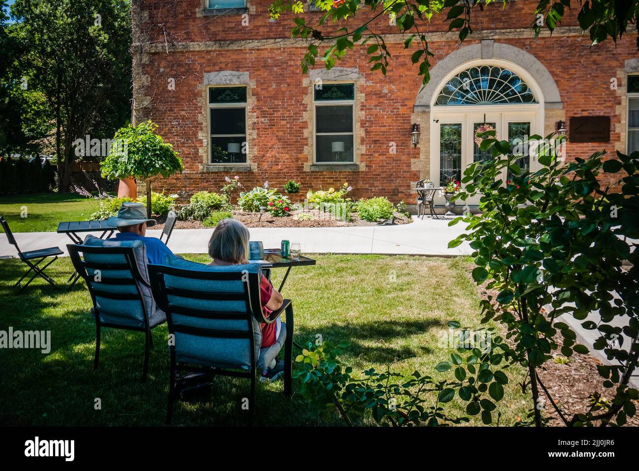 A senior couple relaxing outside in front of a brickhouse summer Stock Photo