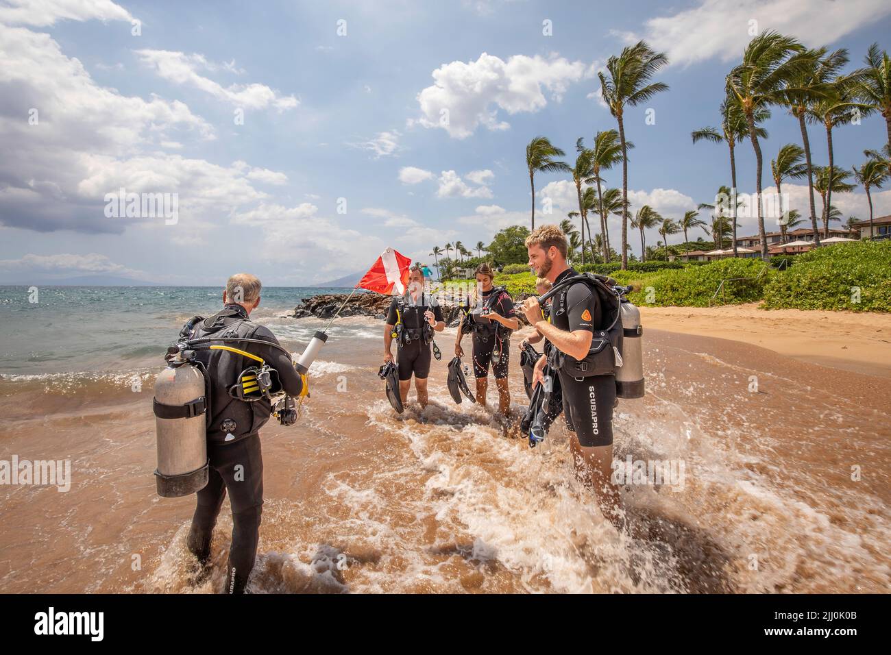 SCUBA diving instructor Anthony Manion entering the ocean with four students in front of the Grand Wailea Hotel on Maui, Hawaii. All five individuals Stock Photo