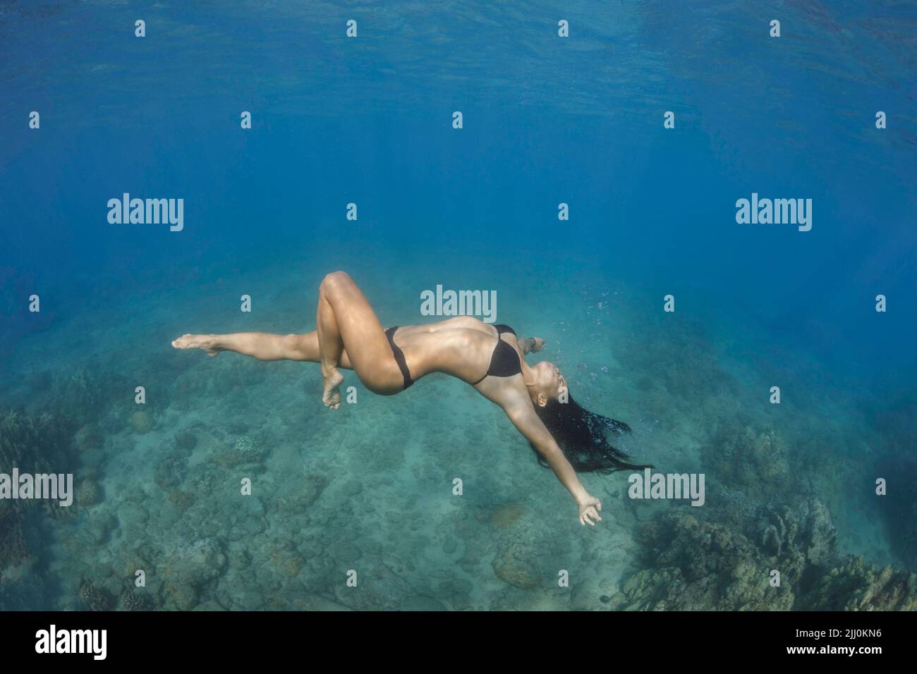 Model Alicia Yamada (MR) strikes a pose underwater in Kapalua Bay, Maui, Hawaii, USA. Stock Photo