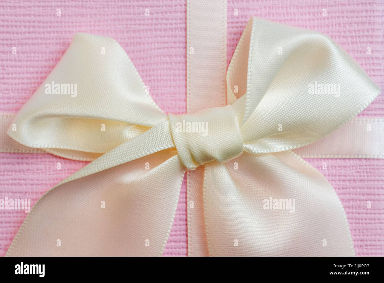 Close up of a beautiful bright bow with satin ribbon on a pink gift box. Greeting card for Grandma's day. Copy space for text. Stock Photo