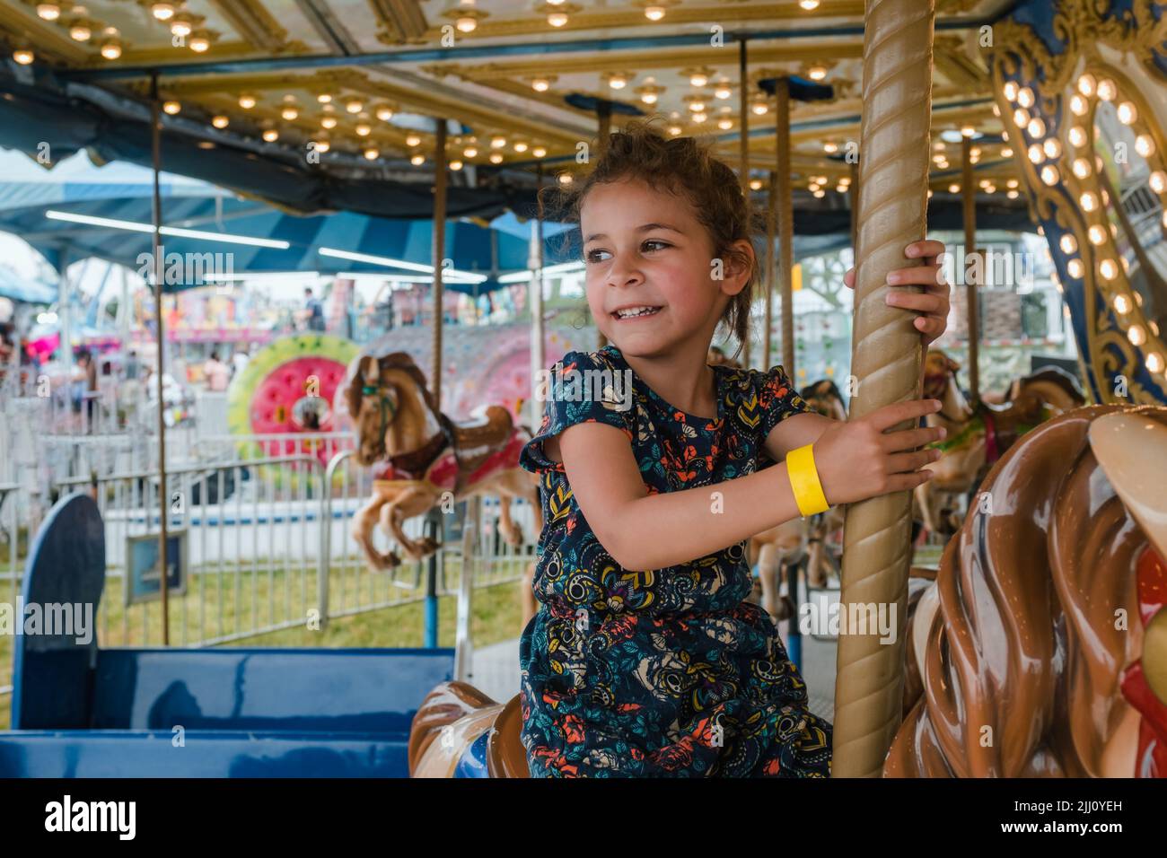Cute multiracial girl riding on carousel Stock Photo