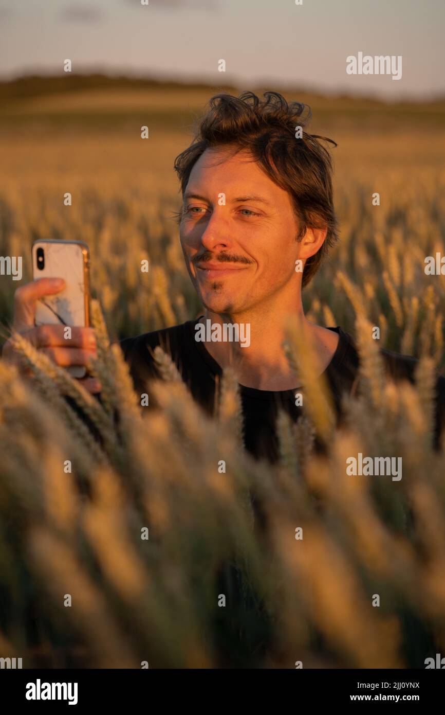 Young cheerful excited man wearing t-shirt standing in wheat field Stock Photo