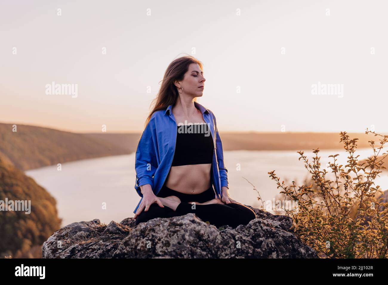 View of Concentrated woman in lotus pose doing meditation on high rock Stock ...