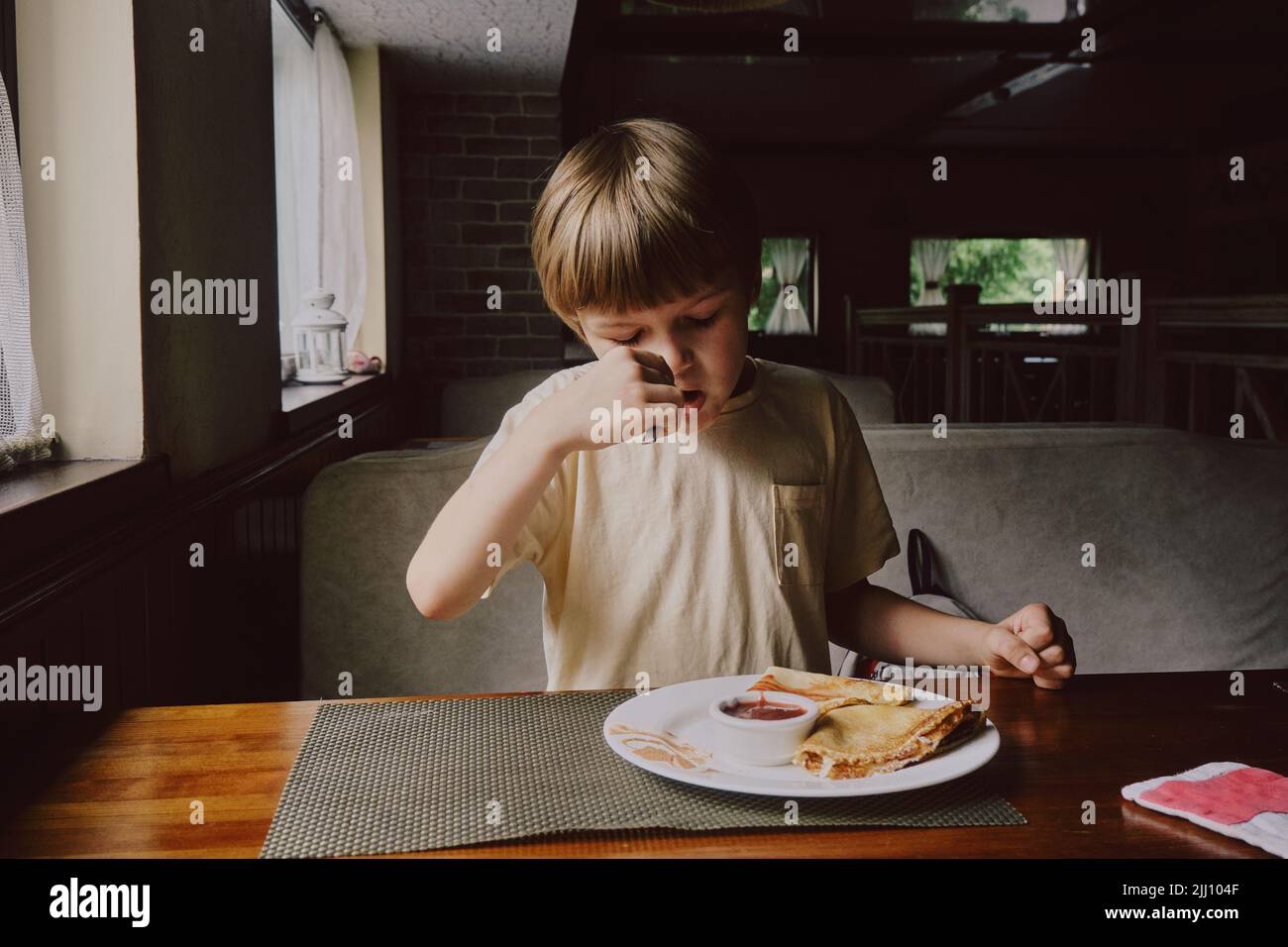 Cute healthy preschool kid boy eats in cafe. Stock Photo