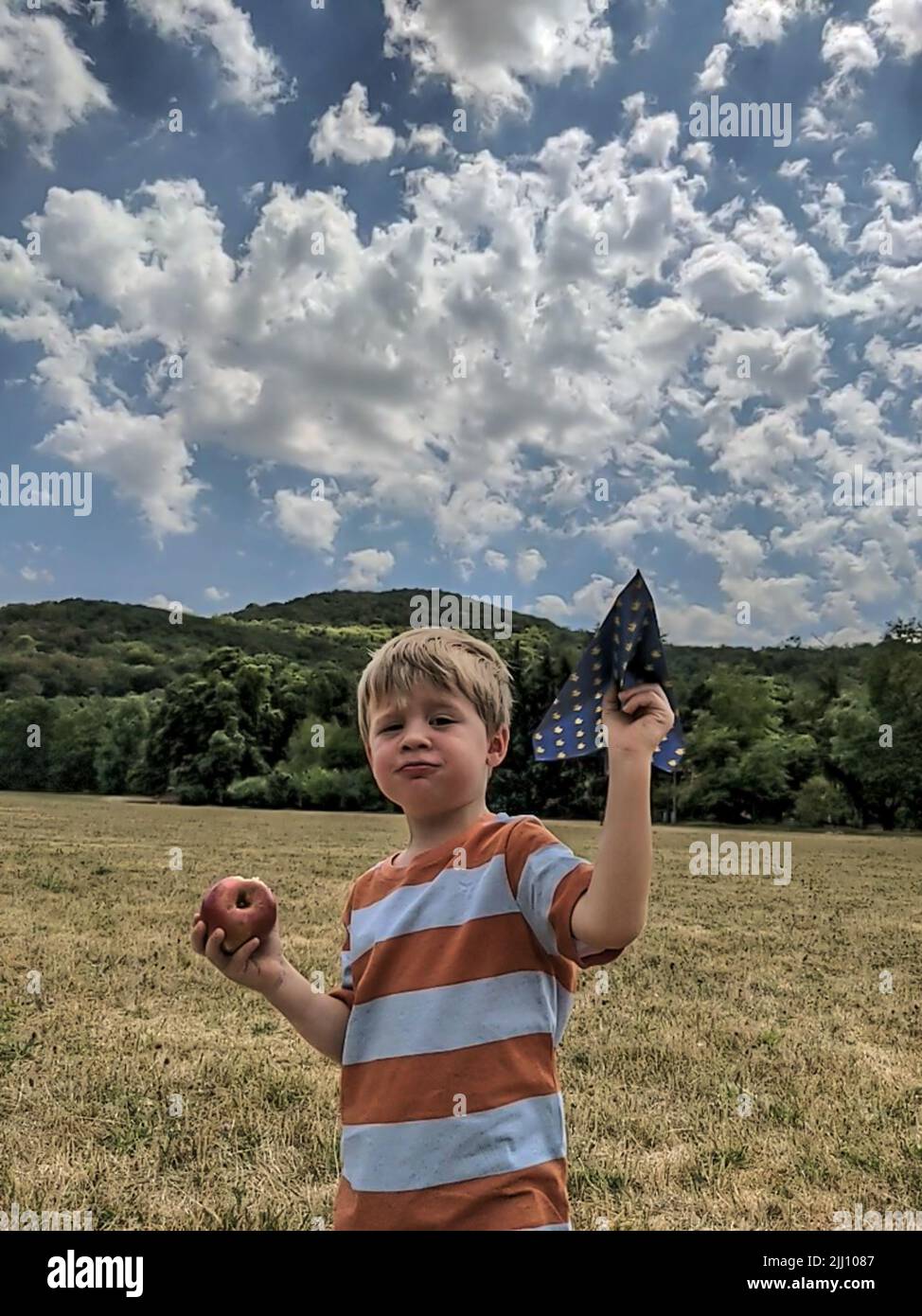 A boy with an apple is holding a paper airplane Stock Photo