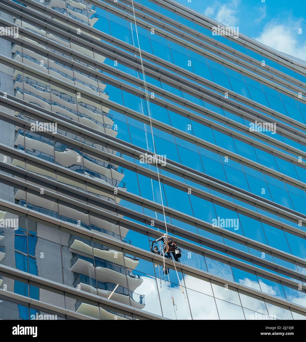 hardworking man cleaning window glass of skyscraper Stock Photo