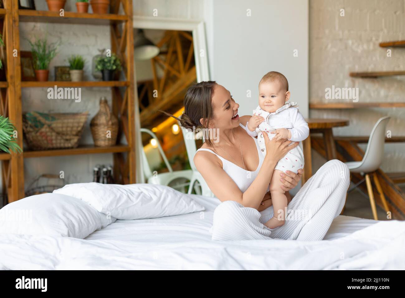 Happy young mother and her baby girl smiling and looking each other. Stock Photo